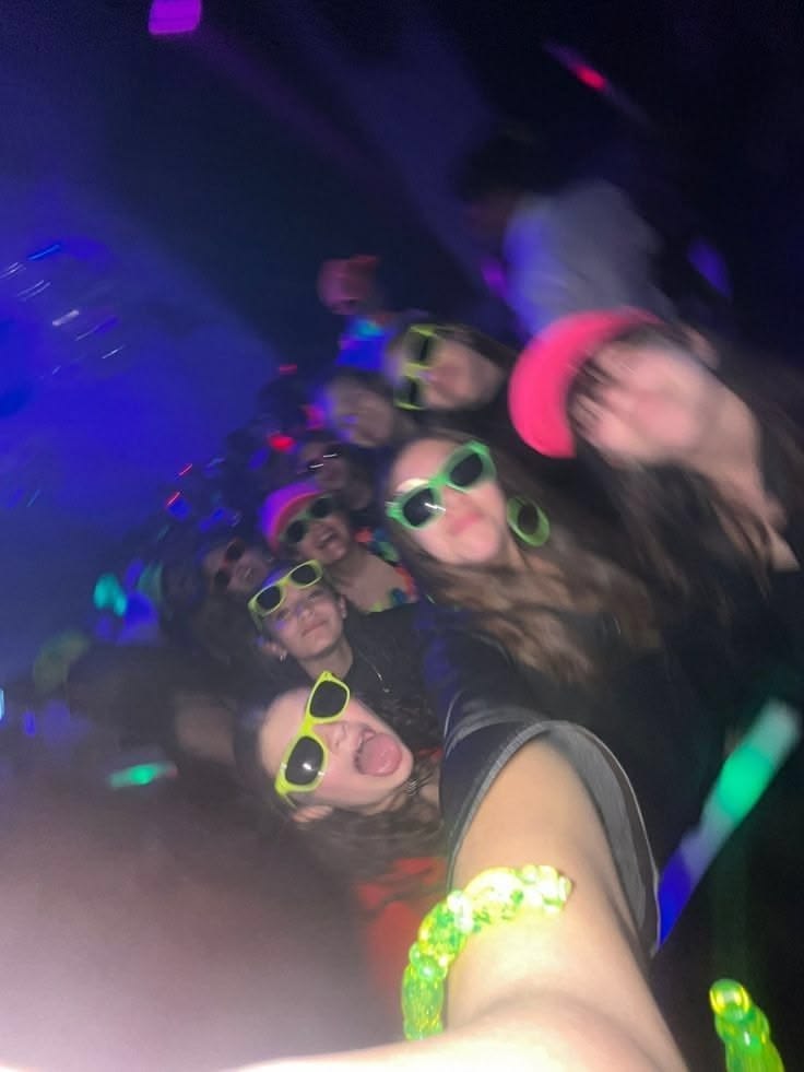 Grupo de amigos con lentes de sol verde neón y pulseras luminosas en una fiesta