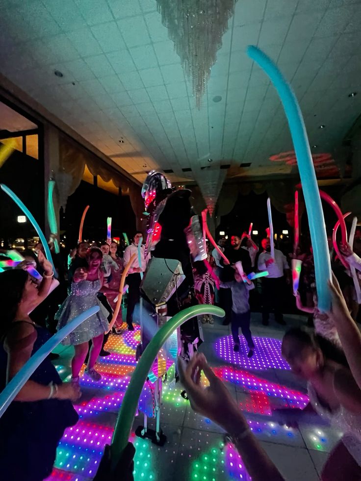 Pista de baile con luces LED y globos largos en un salón de XV años